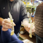 Ein Mann hält in der linken Hand die Griffschalen eines Taschenmessers aus Hirschhorn und in der rechten Hand ein fertig zusammengebautes Taschenmesser