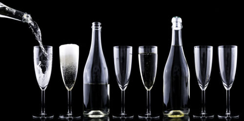 Sektgläser und Champagnerfalschen vor schwarzem Hintergrund